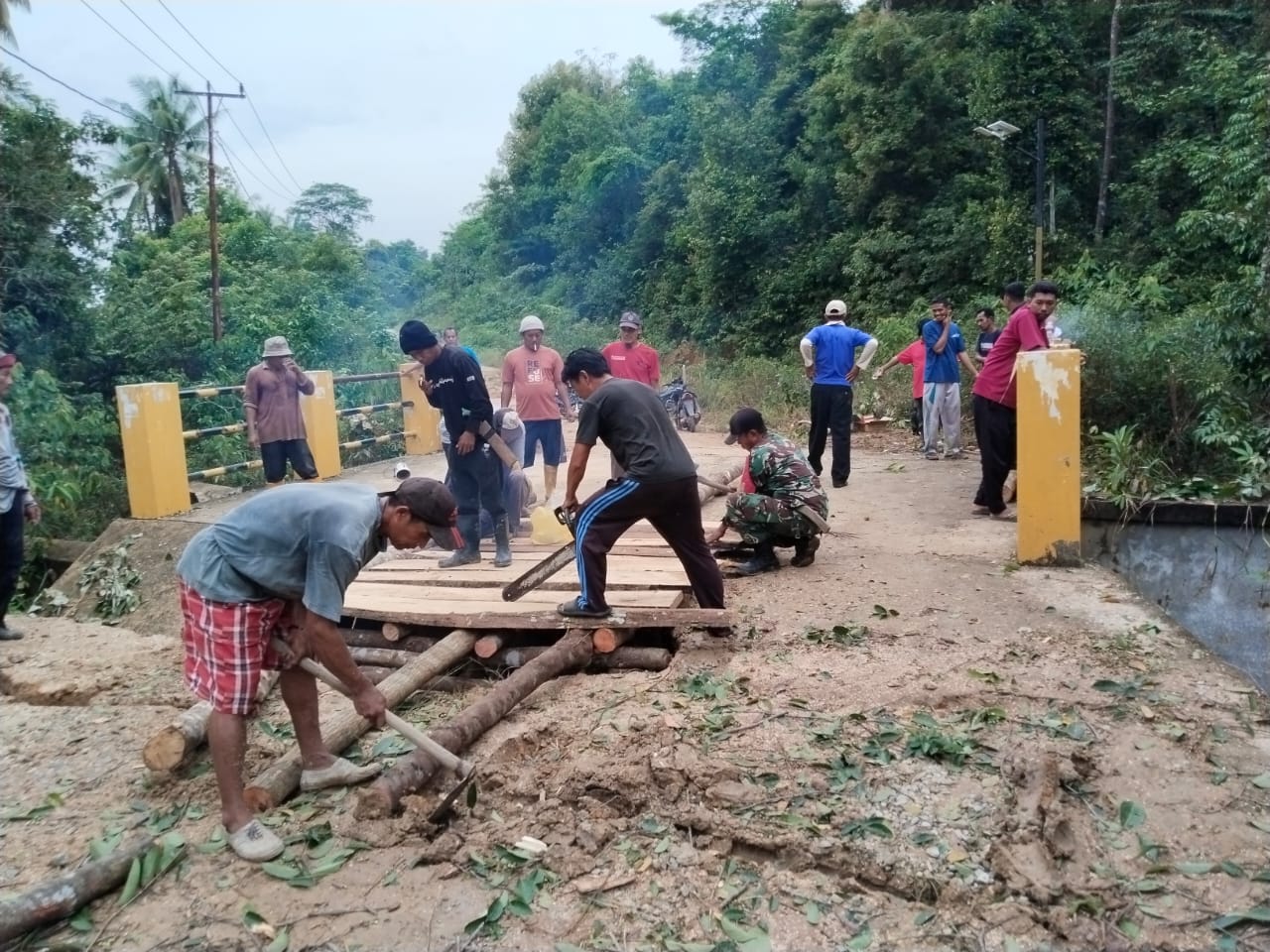 Babinsa Desa Sugie, Serma M. Amin bersama warga masyarakat Desa Niur Permai, melaksanakan gotong royong memperbaiki jembatan.