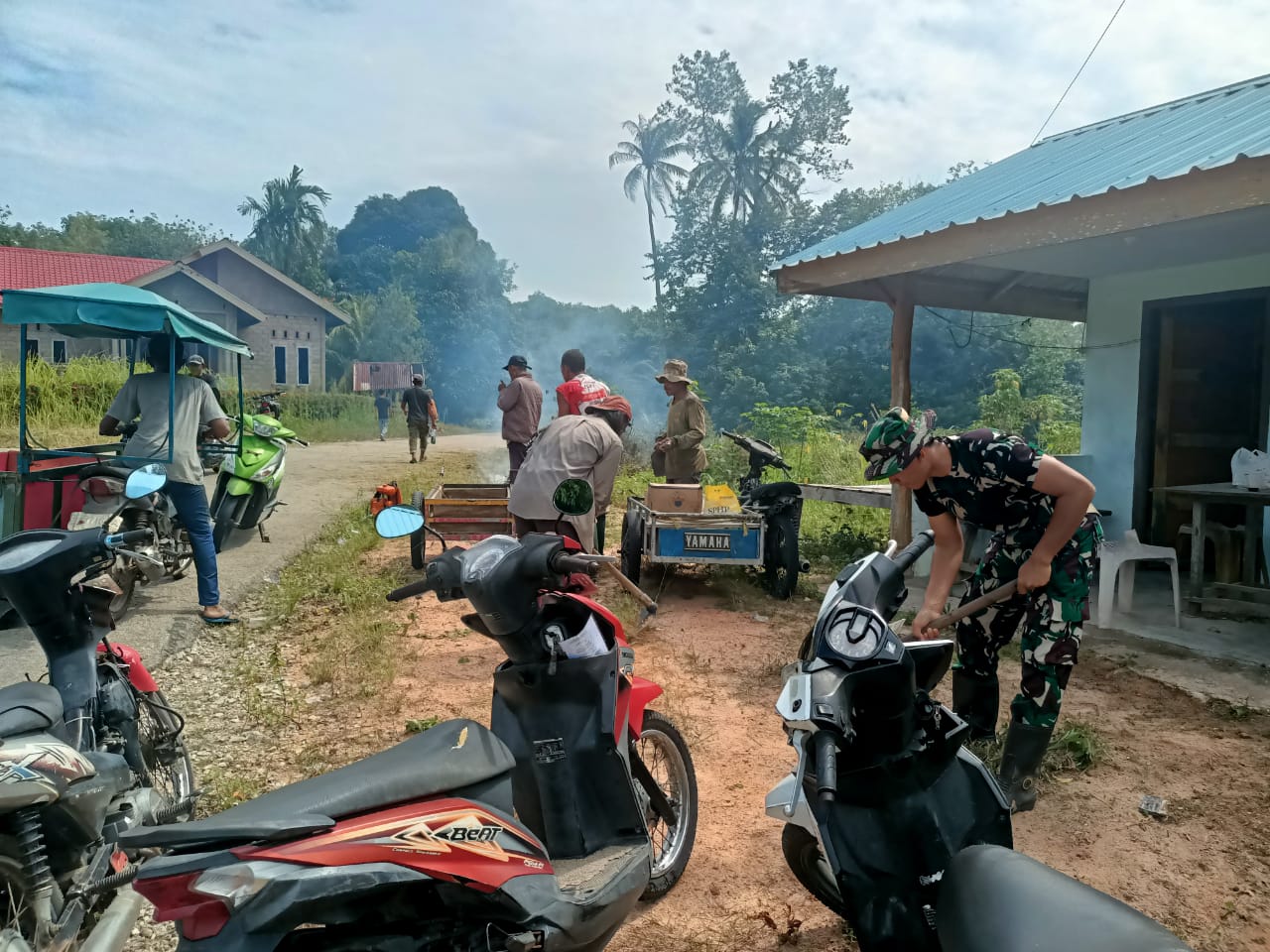 Dua Babinsa dari Koramil 02/Moro, Serda Benny Murdani dan Praka Irvan mengajak warga gotong-royong membersihkan jalan  Kp. Sidodadi.