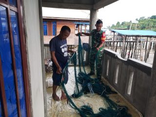 Babinsa Keban Praka Randi Bantu Nelayan Perbaiki Jaring Tangkap Ikan